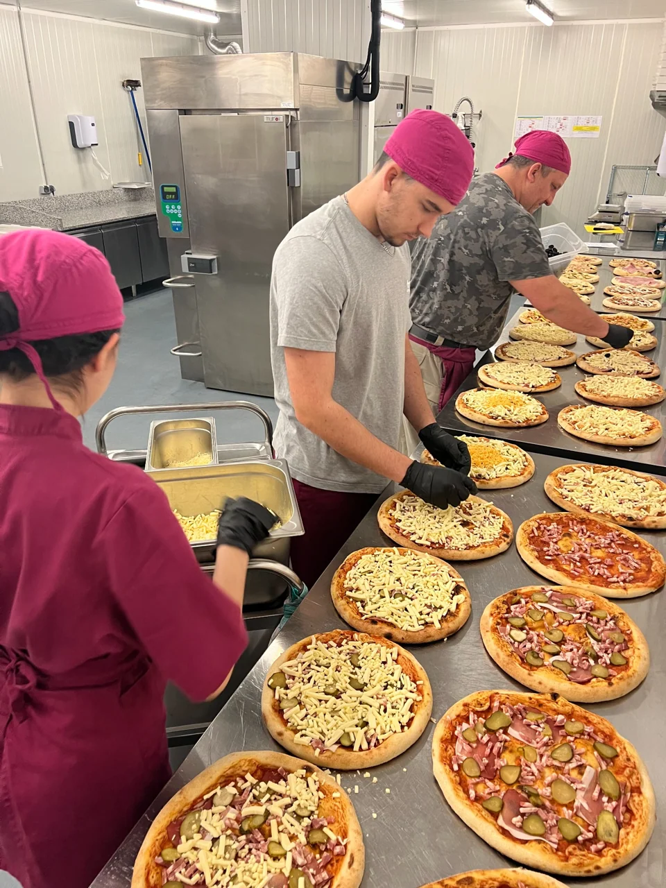 Garnissage à la main des pizzas dans le laboratoire